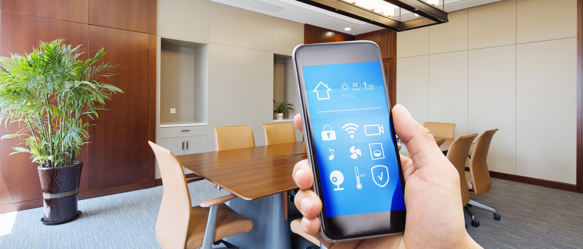 Ein Smartphone auf dem eine Workspace Management App angezeigt wird, im Hintergrund ein Konferenzraum