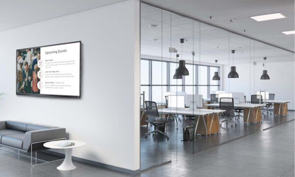 Blick in ein modernes Büro, im Foyer eine Sitzecke, dahinter an der Wand ist ein Display mit wichtigen Informationen 