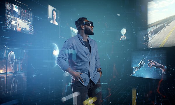 Mann mit Virtual Reality Brille, Apple Vision Pro, steht in einem Raum mit viel Blau, um Ihn herum sind Bilder eingeblendet, die er sieht, eine Menschliche Hand und eine Roboterhand, die sich am Finger berühren, eine Straße, die Bilder drücken Fortschrittlichkeit aus 