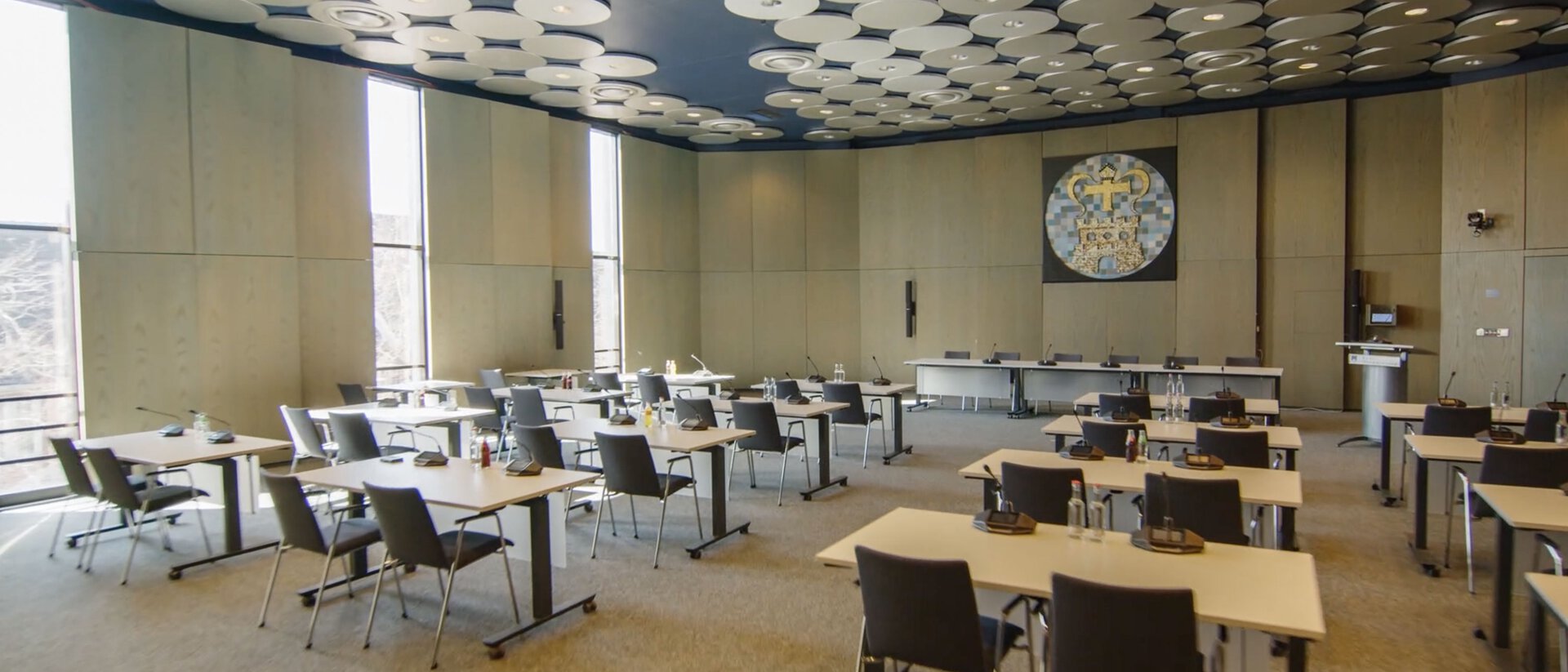Ein Bild eines leeren Sitzungssaales mit mehreren Sprechstellen und einem großen Podium an der Stirnseite