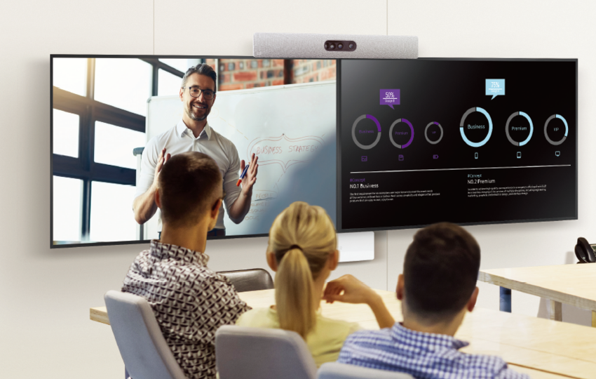 Drei Personen sitzen in einem Konferenztisch und halten eine Videokonferenz über Cisco Webex ab, auf dem Display ist die Cisco Webex Room Bar installiert