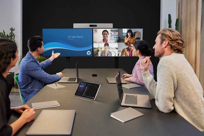 Eine Gruppe die in einem Konferenzraum sitzt und auf ein Dual-Display mit Cisco Videobar sieht und per Microsoft Teams ein Meeting abhält
