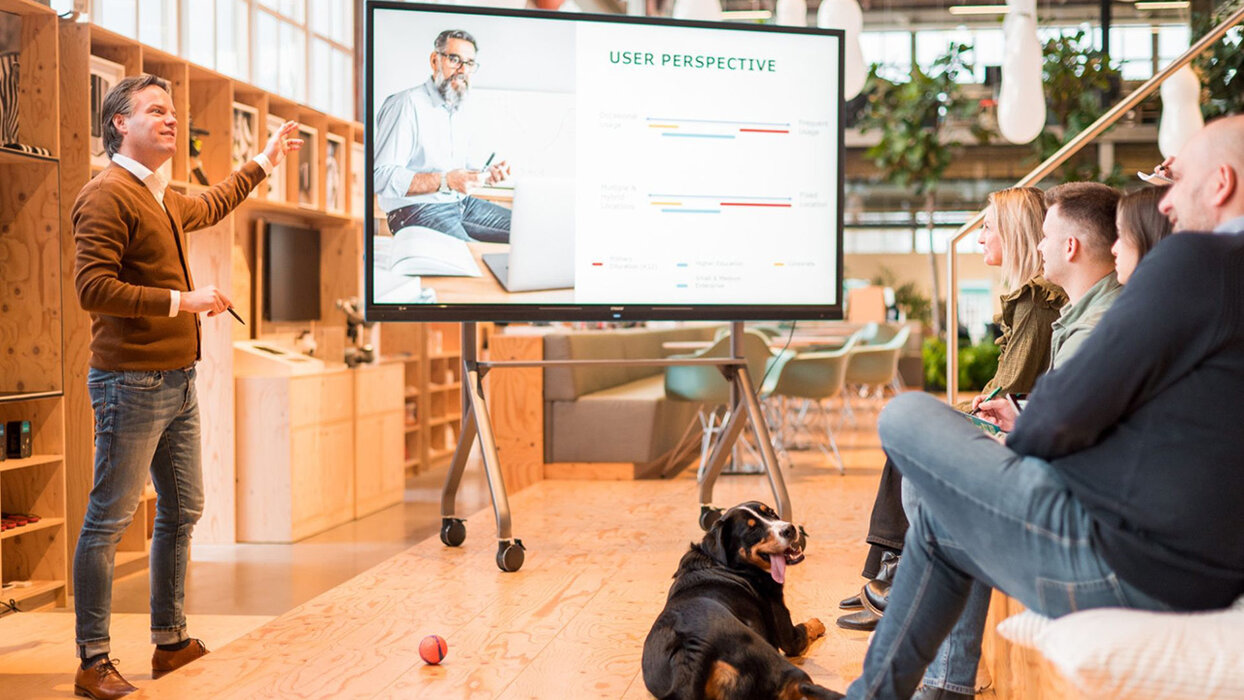 Ein Mann steht neben dem CTOUCH Neo in einer art Hörsaal, mehrere Personen hören ihm zu